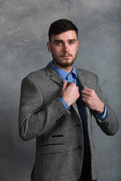 Yakışıklı şık genç adam gri arka plan üzerinde iç ayakta