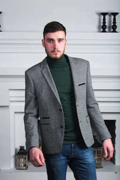 Handsome stylish young man standing in interior on white background — Stock Photo, Image