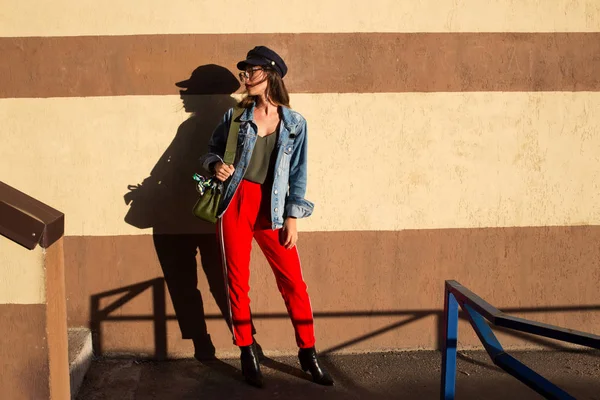 Молодая довольно хипстерская веселая девушка позирует на улице в солнечный день, развлекаясь в одиночестве, стильная одежда и очки — стоковое фото