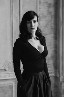 İç stüdyoda siyah seksi elbise ayakta genç güzel kadın model siyah ve beyaz portre.