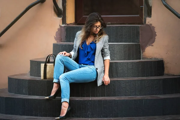 Modelo de moda en la calle. Hermosa mujer sexy en ropa de otoño de moda con estilo sentado en las escaleras — Foto de Stock