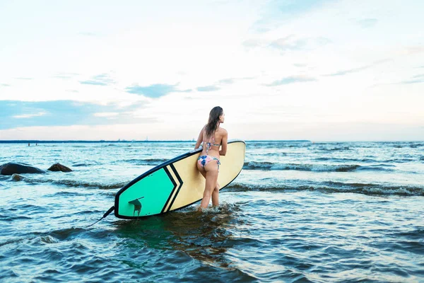 Beautiful fit surfing girl on surfboard on in the ocean. Woman ride good wave.