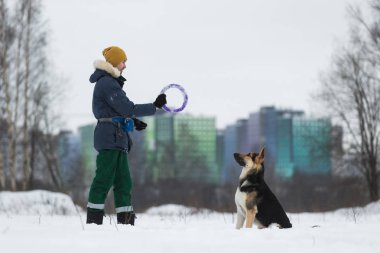 Man playing with a German shepherd in the Park in the winter clipart