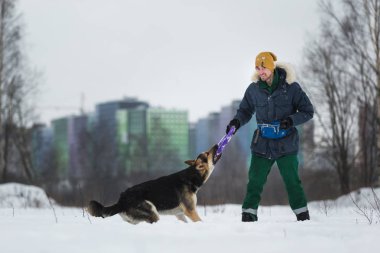 Kışın Parkta Bir Alman çoban köpeğiyle oynayan bir adamın portresi