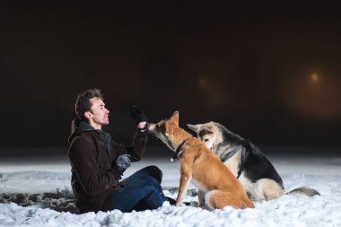 Kışın gece yarısı iki köpeği olan bir adama yan bakış.