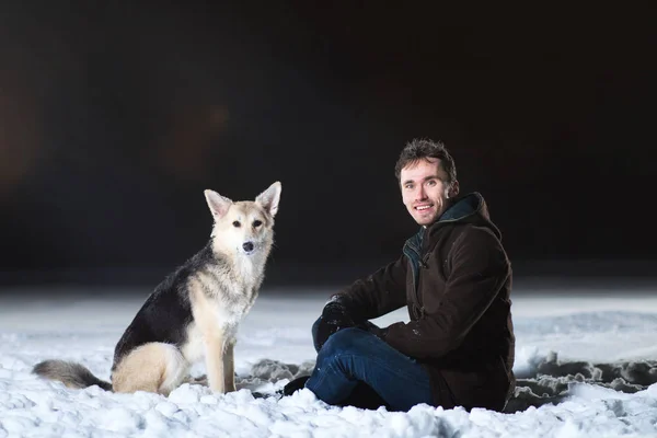 Vista lateral a un hombre con dos perros por la noche en invierno — Foto de Stock