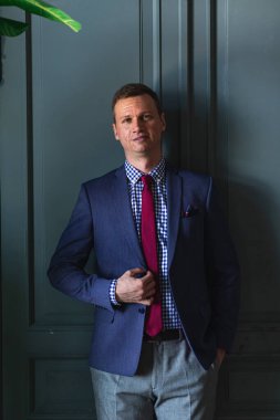 Uzun boylu, mavi takım elbiseli, kırmızı kravatlı, iç çamaşırı giymiş.