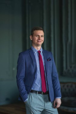 Uzun boylu, mavi takım elbiseli, kırmızı kravatlı, iç çamaşırı giymiş.