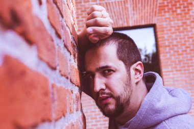 genç adam bir tuğla duvara yaslanmış