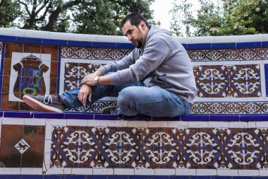 Genç adam Arap tarzı bir bankta yaslanmış