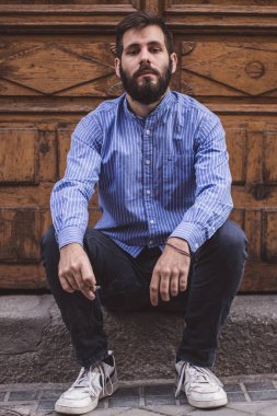 bir sakallı bir kapısında oturan ve sigara