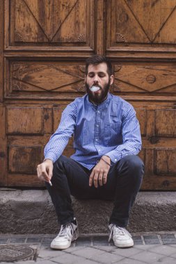 bir sakallı bir kapısında oturan ve sigara