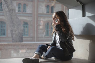 pencerenin önünde oturan telefonda konuşan kız