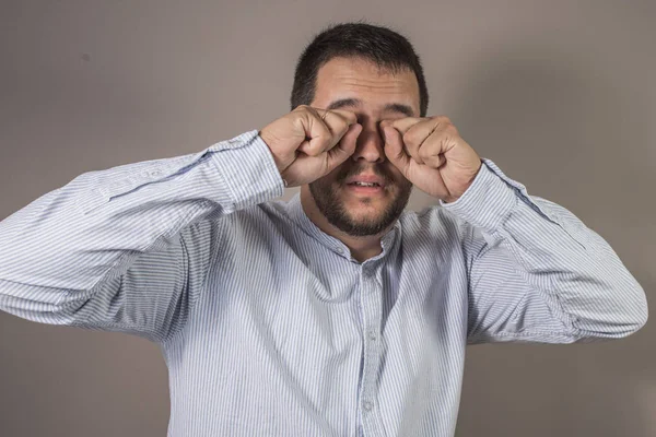 man scratching his eyes with the glasses removed