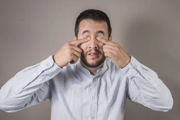 man scratching his eyes with the glasses removed