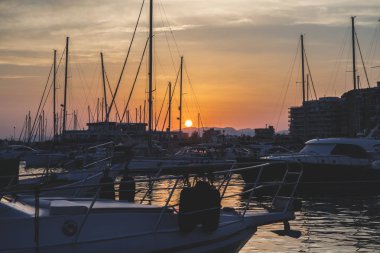 önünde güneş batımında tekneler limanda palamarla