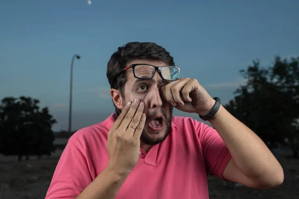 portrait of young man scratching an eye with glasses