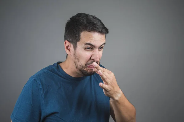 man pulling something out of his tongue with a face of disgust