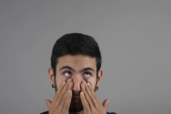 Young man scratching his eyes with his hands