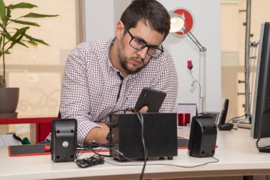 Genç adam ofiste akıllı telefon kullanıyor.