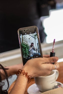 Genç bayan, akıllı telefon kamerasıyla makyaj yapıyor.