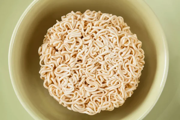 Close up Raw Instant noodles isolated on a green bowl.