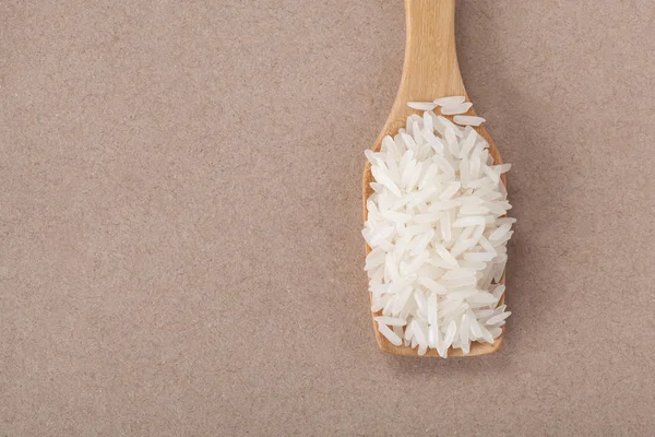 Uzavřete rýži na dřevěné lžičce na hnědém papíře s prostorem pro kopírování. — Stock fotografie