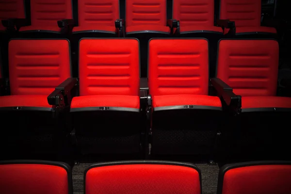 As cadeiras vermelhas sem pessoas no cinema, fundo embaçado . — Fotografia de Stock