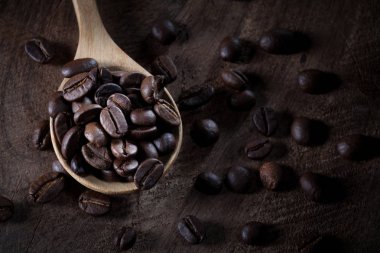 kahverengi ahşap masada tahta kaşık üzerinde kahve çekirdekleri.