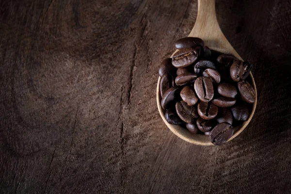 Coffee beans on wooden spoon on the brown wood table. — Stock Photo, Image