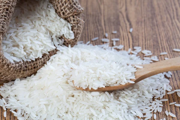 Rýže v pytlech a dřevěná lžíce pro dřevěný stůl — Stock fotografie