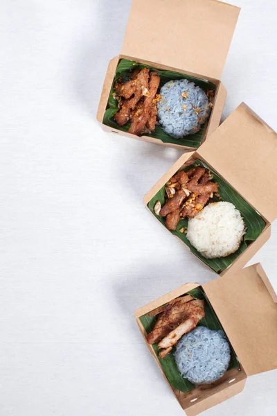 Липкий рис с жареной свининой и жареной свининой в коричневую бумажную коробку — стоковое фото