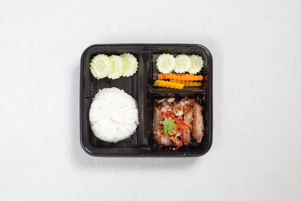 마늘 과 후추와 쌀을 곁들인 튀긴 돼지고기와 검은 플라스틱 상자에 넣는다 — 스톡 사진