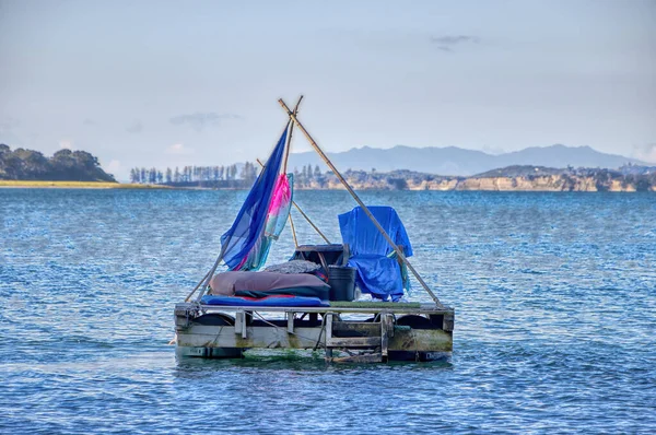 A self-made Pontoon Boat with bright colors drifting on the sea/water. It resembles a beautiful hippy culture