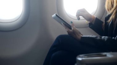 Tabletle rahat bir uçakta oturan kadın