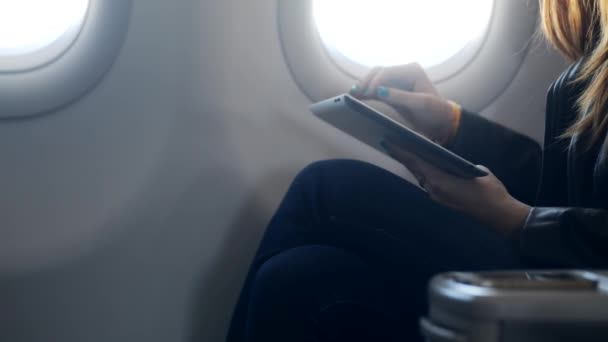 Señora sosteniendo tableta moderna en las manos y sentado en el avión — Vídeos de Stock