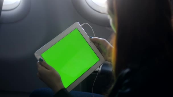 Mulher jovem olhando para a tela do tablet e sentado no avião — Vídeo de Stock