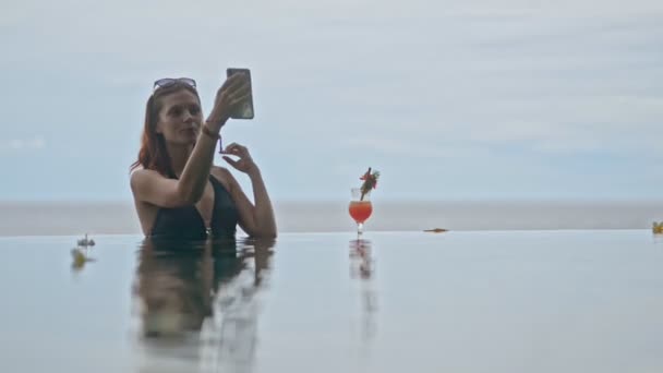 Happy american woman taking selfie photo is in poolside on blue background. — Stock Video