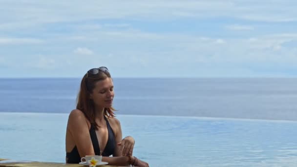 Retrato de mujer joven está viendo paisaje marino beber café en la piscina del complejo . — Vídeos de Stock