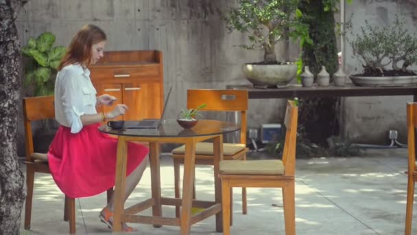 Jonge Amerikaanse vrouw die koffie drinkt tijdens online winkelen bij de balie in het zomercafé. — Stockvideo