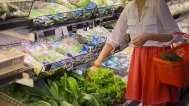 Genç beyaz kadın alışveriş organik dükkanda ayakta yeşil salata satın alma.