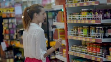 Bakkalda yürüyen lezzetli konserve zeytin seçen genç kadın müşteri.