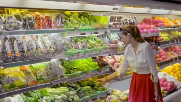 Junge Amerikanerin wählt und riecht grünen Salat im Supermarkt. — Stockvideo