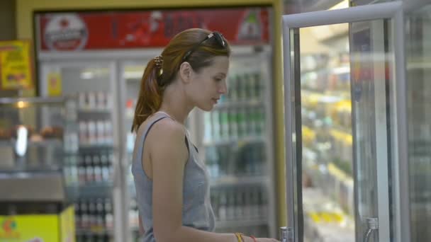 Joven hermosa mujer elegir el agua mineral en el supermercado, mientras que los viajes de Asia . — Vídeos de Stock
