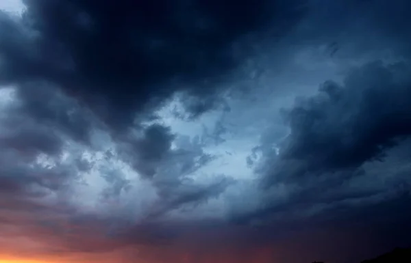 Delightful stormy sky with amazing dark blue clouds at sunset background