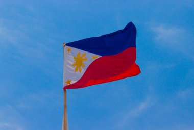 Temiz mavi gökyüzü karşı rüzgarda sallayarak bayrak direğine Filipinler bayrağı