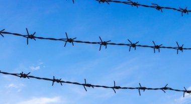 Dikenli tel parlak mavi gökyüzü arka plan üzerinde genellikle ceza, ülke sınırları ve özel mülkiyet çevreler. Kavramı kopya alanı için yasak bölge, yasadışı göç Temalar, hapis cezası ile