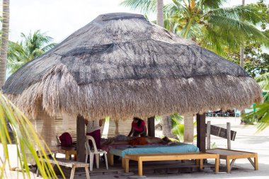 Palawan, Filipinler - 27 Eylül 2018: Asyalı kadın masaj terapisti kızlara masaj yapıyor. Genç kadın Spa zevk tropikal plaj açık havada masaj. Masaj çardağın altında Hindistan cevizi hurma ağacı