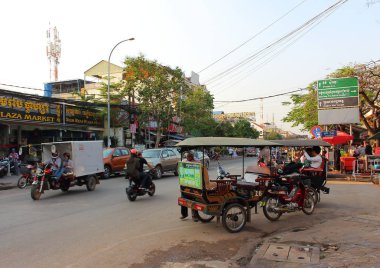 Siem Reap, Kamboçya - Mart 24, 2018: Trafik Siem Reap şehir bir yolda. Tuk Tuk taksi yolcu için bekleyen caddenin üzerinde. Tuk Tuk popüler turizm ulaşım ve Kamboçya kültürünün sembolü