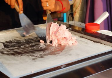 Asya heyecan yapma süreci spatula ile rulo dondurma meyve ve krema bir buz tavada kızarmış. Bulanık hareket el ve zaman pişirme spatula. Seçici odak